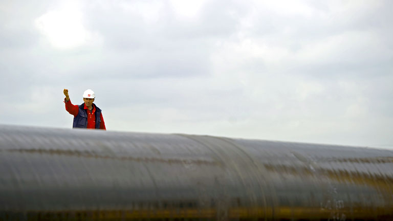 Ein Arbeiter steht an einer Pipeline.