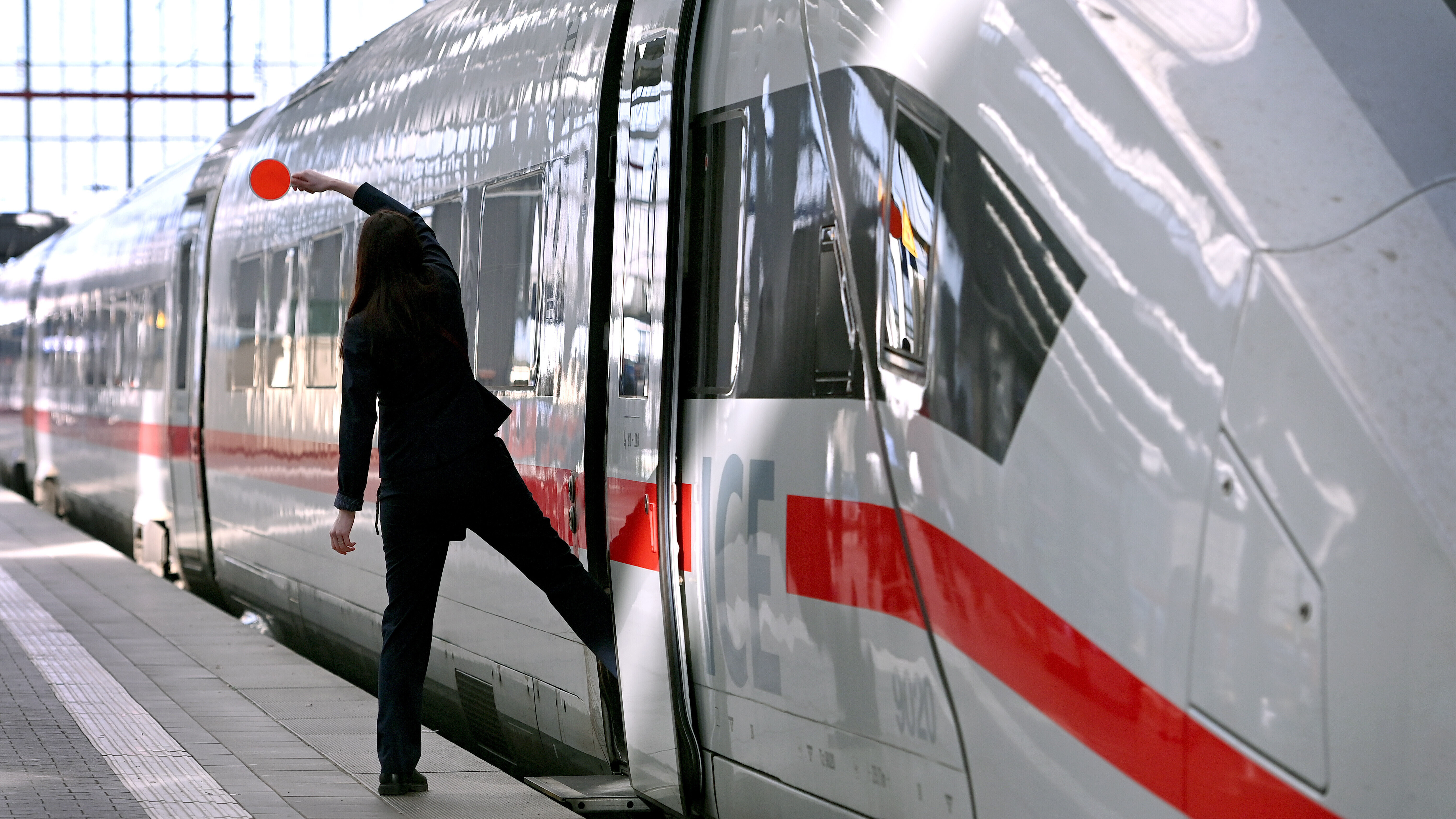 Zugbegleiterin signalisiert dem Lokfuehrer mit roter Kelle, dass der ICE zur Abfahrt bereit ist.