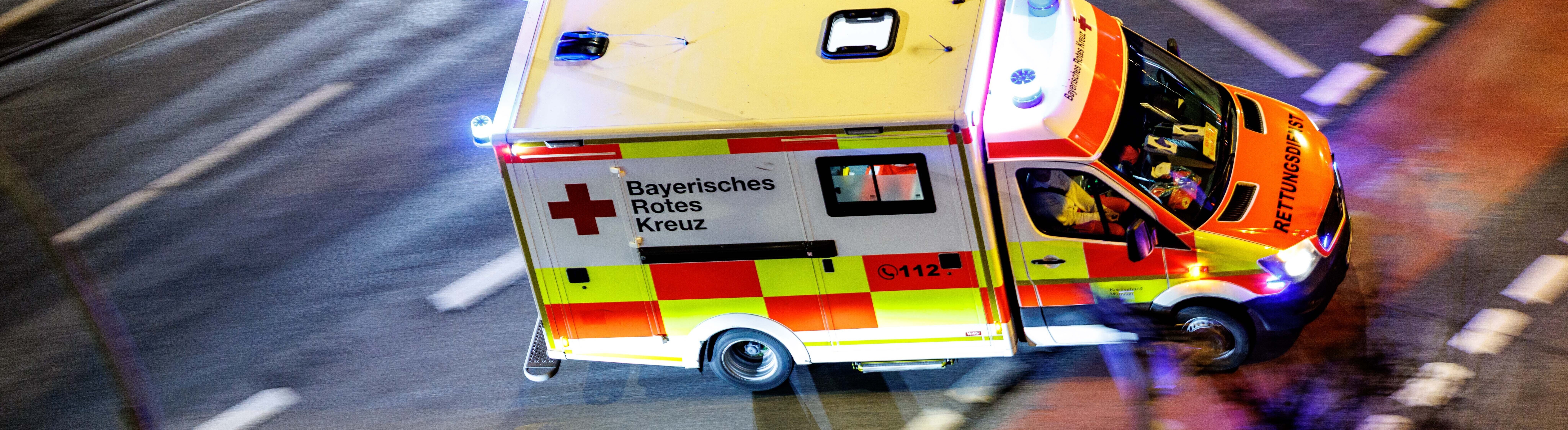 Ein Krankenwagen vom Bayerischen Roten Kreuz mit eingeschaltetem Blaulicht.