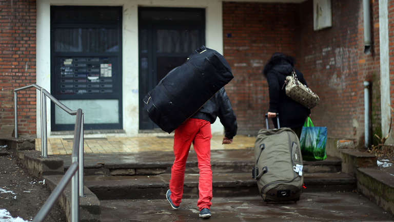 Bewohner gehen mit Gepäck am 14.03.2013 in Duisburg (Nordrhein-Westfalen) in ein in Duisburg oft als "Problemhaus" bezeichnetes Gebäude.