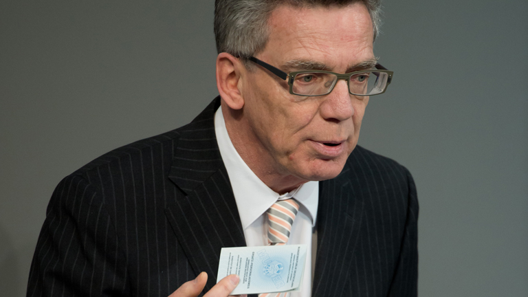 Bundesinnenminister Thomas de Maiziere (CDU) zeigt am 30.01.2015 während der Bundestagssitzung in Berlin während seiner Rede zum Personalausweisgesetz ein Muster für einen Ersatzausweis.