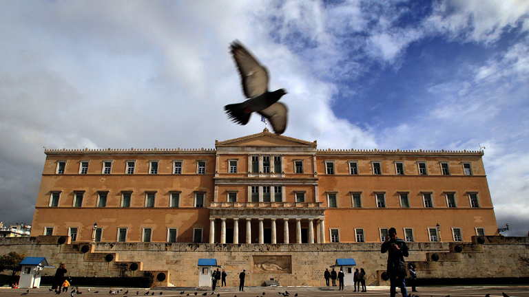 Eine Taube fliegt über das griechische Parlament in Athen