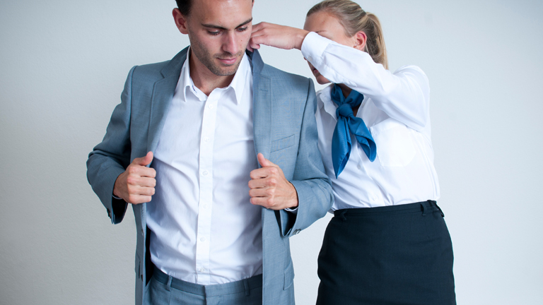 Eine Frau hilft einem Mann ins Jacket