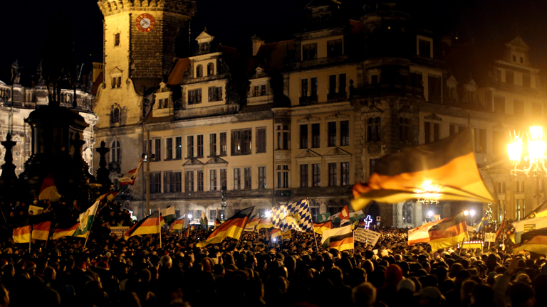 Anhänger des Pegida-Bündnisses (Patriotische Europäer gegen die Islamisierung des Abendlandes) demonstrieren am 22.12.2014 in Dresden (Sachsen) gegen die angebliche Überfremdung durch Flüchtlinge und schwenken Deutschlandfahnen.