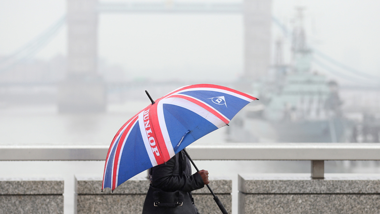 Eine Frau geht am 06.11.2013 mit einem Union-Jack-Regenschirm vor der Tower Bridge in London (England) entlang.
