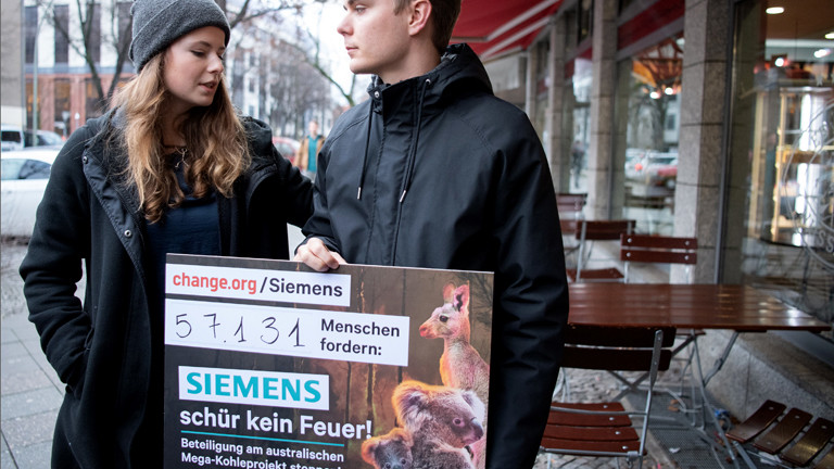 Frau und Mann mit einem Plakat: "Siemens, schür kein Feuer!"
