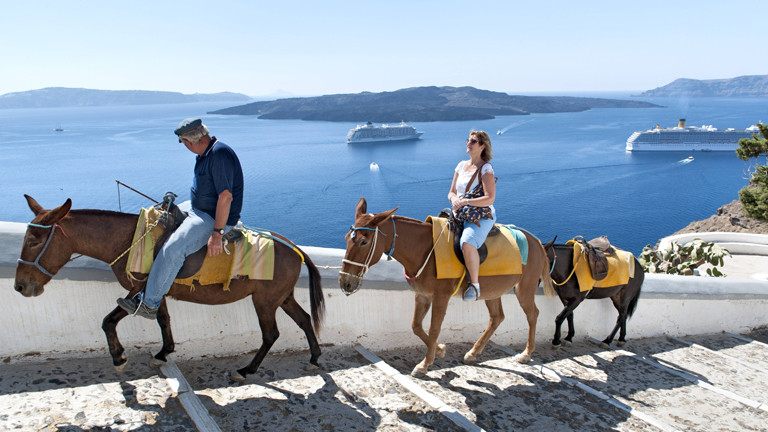 Eselguide, Touristin und drei Esel auf der griechischen Insel Santorin