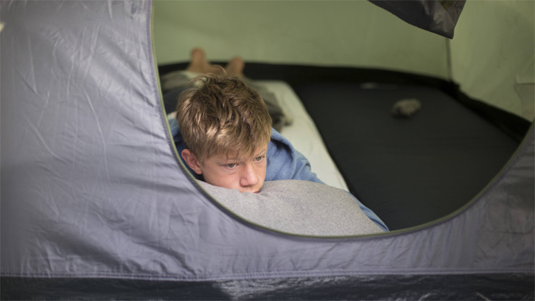 Unser Symbolbild zeigt einen Jungen der im August 2018 aus einem Zelt in Dülmen guckt