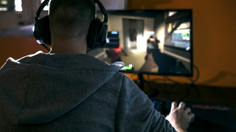 Mann sitzt vor einem Rechner und spielt Computerspiele