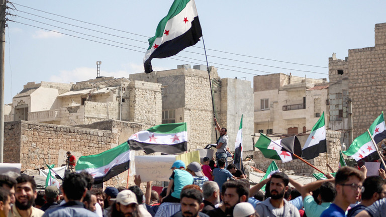 Menschen schwenken Fahnen der Opposition in Idlib.