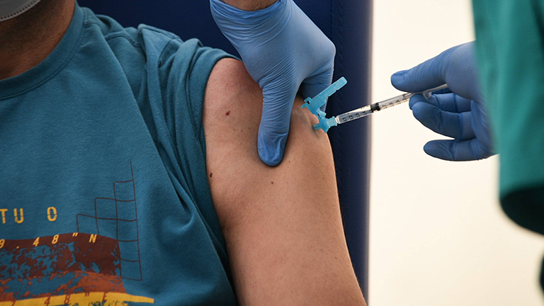 Mensch bekommt Impfspritze in den Oberarm