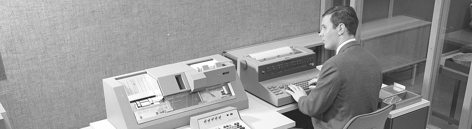 Schwarz-weiß Foto eines Mannes, der in den 1960er Jahren an einem Teil des Computers IBM System 360 arbeitet.