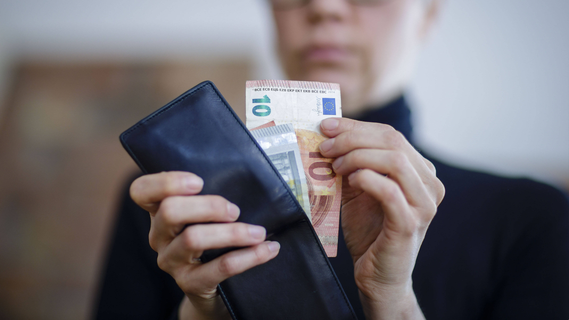 Frau zieht Euro-Scheine aus einem Portemonnaie