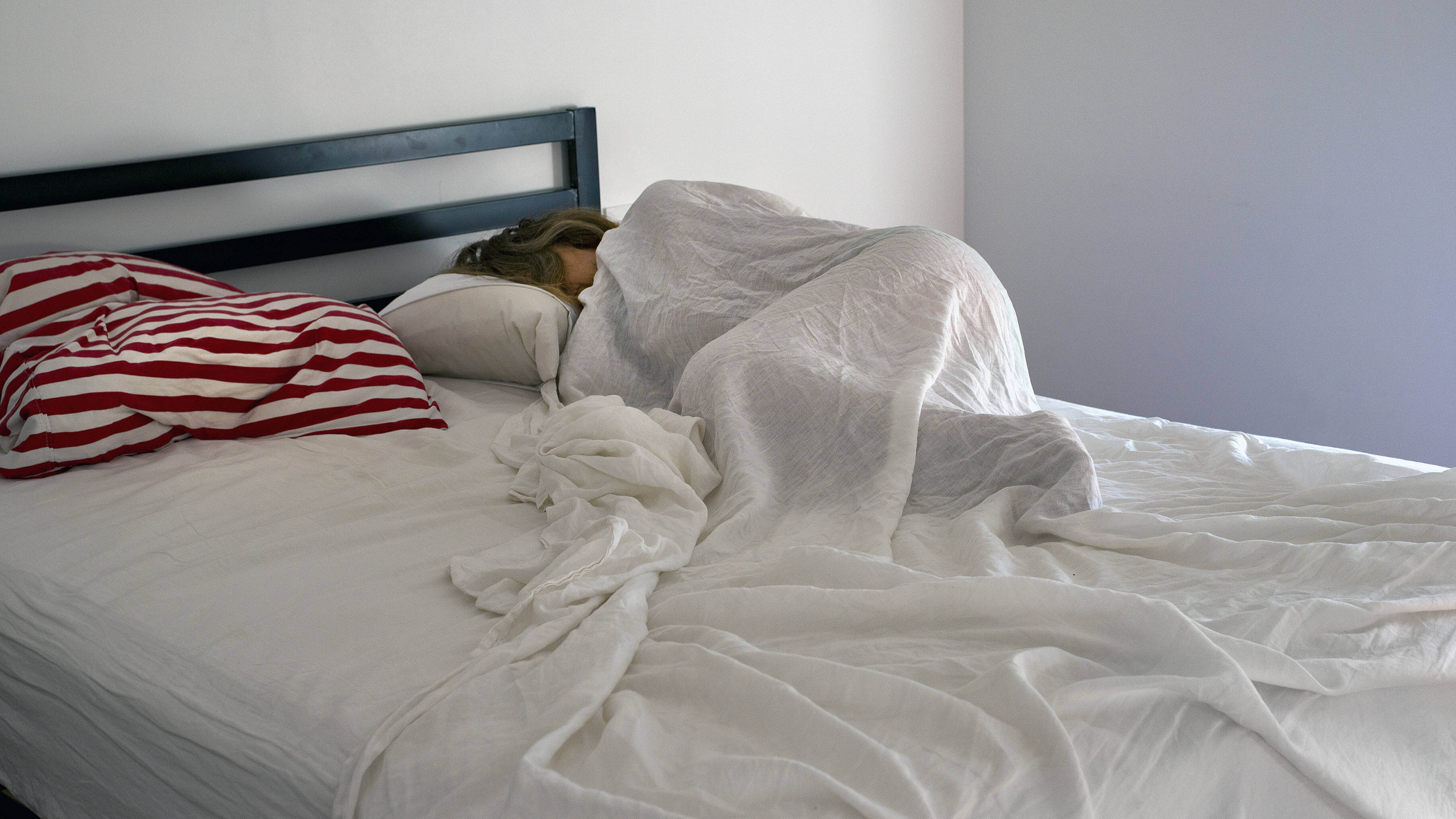 Eine Frau liegt im Bett mit der Decke über ihrem Körper