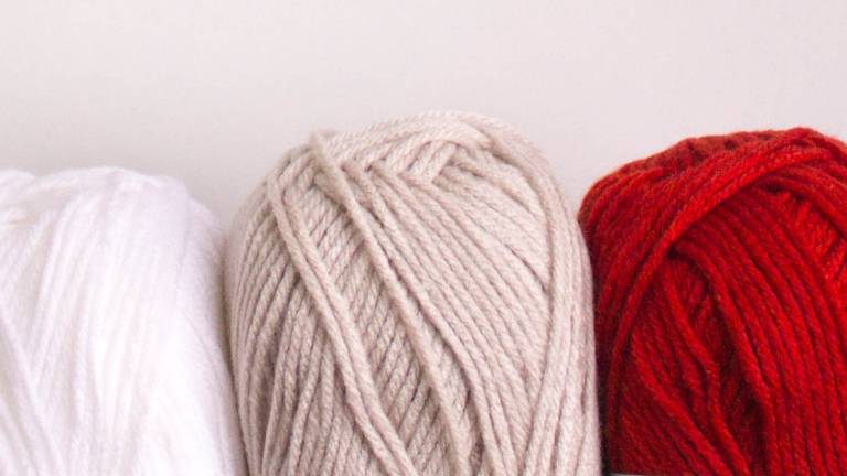 Drei Wollknäul in den Fraben rot, beige und weiß
