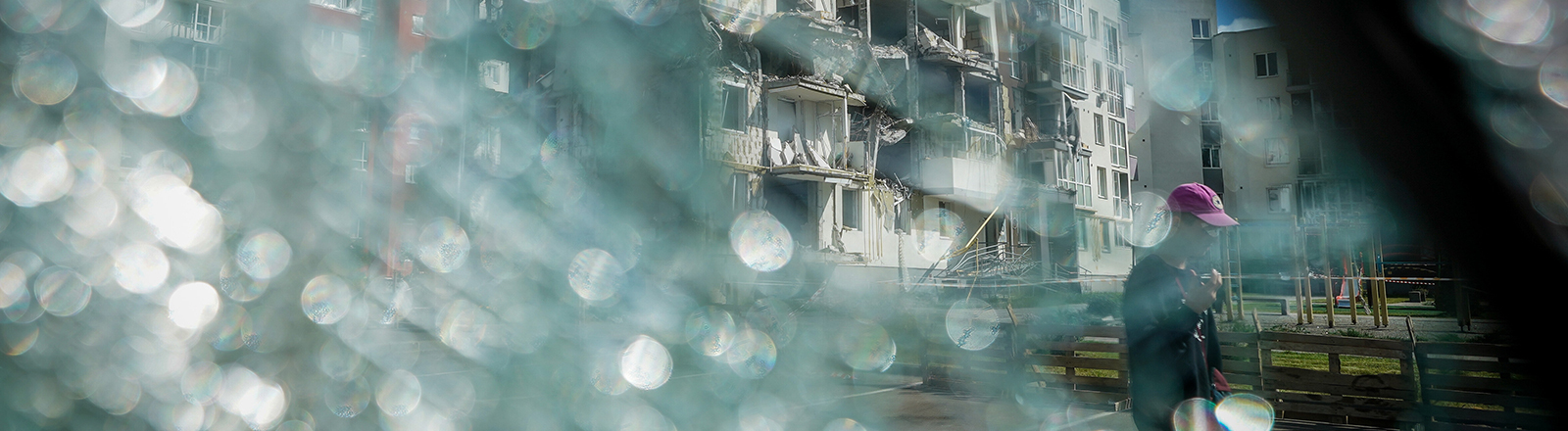 Durch eine zerbrochene Windschutzscheibe ist ein zerstörtes Wohnhaus in Butscha bei Kiew zu sehen.