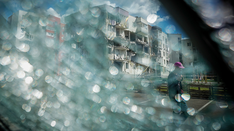 Durch eine zerbrochene Windschutzscheibe ist ein zerstörtes Wohnhaus in Butscha bei Kiew zu sehen.