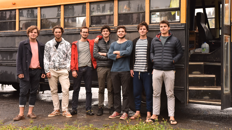 Gruppenbild sieben junger Männer vor ihrem zum Reisebus ausgebauten Schulbus