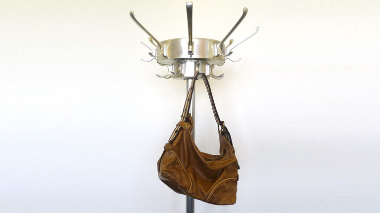 Eine Handtasche hängt an einem Kleiderständer.
