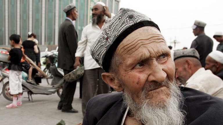 Ein älterer Mann mit Bart sitzt in Kashgar, Xinjiang, am Straßenrand.