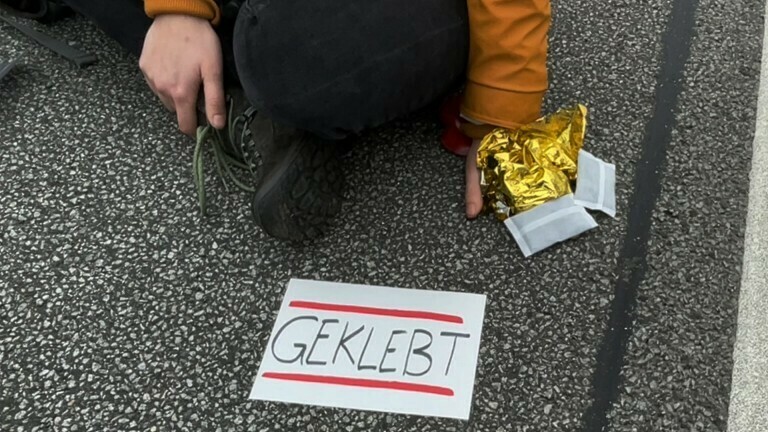«Geklebt» steht auf dem Zettel einer Aktivistin der Gruppe «Aufstand der letzten Generation» auf der Stadtautobahn 100 (A100). Die Aktivisten der Kampagne «Essen Retten - Leben Retten» fordern ein Gesetz gegen Lebensmittelverschwendung und eine Agrarwende, um Treibhausgasemissionen in der Landwirtschaft zu senken
