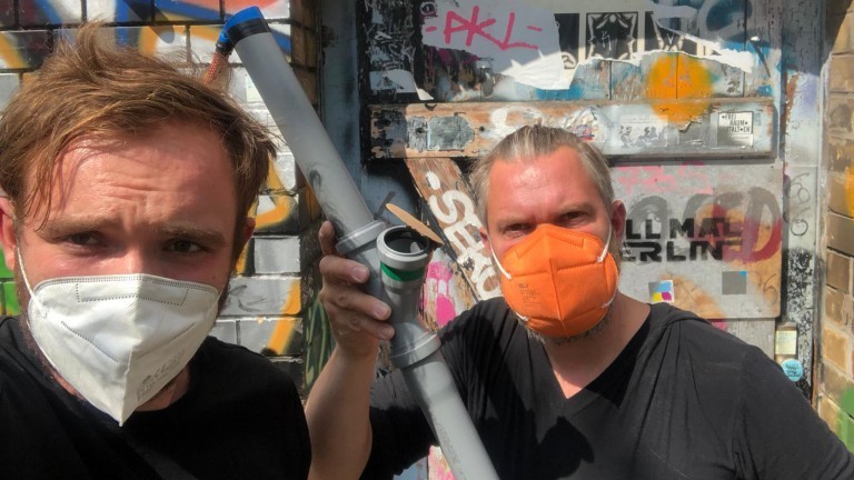 Zwei Männer mit Masken und einem Rohr in der Hand
