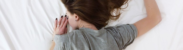 Frau liegt auf einem Bett und schläft