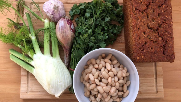 Ackerbohnen, Fenchel, Schalotten und Petersilie liegen auf einem Schneidebrett