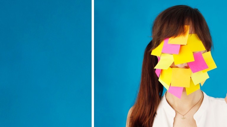 Eine junge Frau hat das Gesicht mit bunten Post-Its zugeklebt.