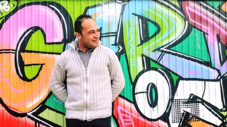 Khalil steht vor einer Graffiti-Wand