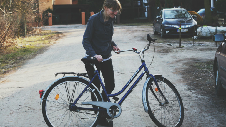 Ein blondes Mädchen schaut auf ein blaues Fahrrad