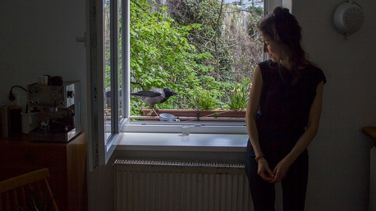 Tabea Hertzog mit einer Krähe an ihrem Küchenfenster.