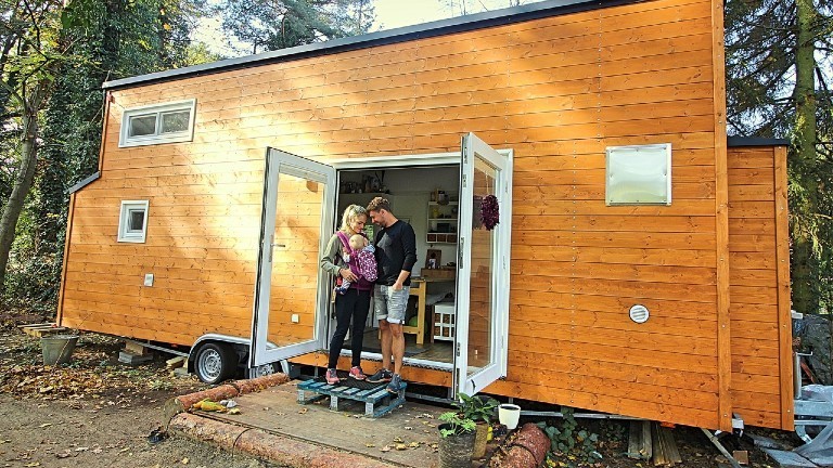 Eine Familie steht vor ihrem Tiny House