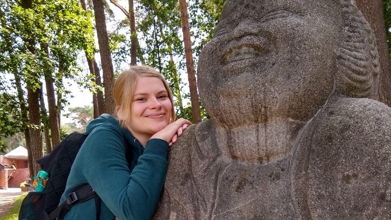 Eva lehnt sich an die Schulter einer Steinskulptur