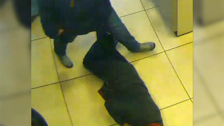 Bilder einer Überwachungskamera: Ein Bankkunde steigt über einen am Boden liegenden Mann hinweg.