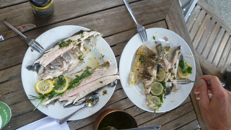 Teller mit den gegrillten Forellen und Gabeln, die reinstechen
