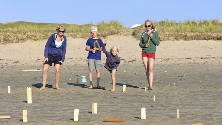 Erwachsene und Kinder spielen Wikingerschach am Strand