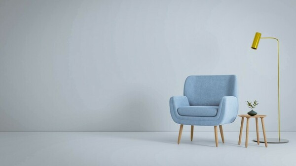 Ein leeres Zimmer, nur ein Sessel, ein Tisch und eine Lampe stehen in einer Ecke.