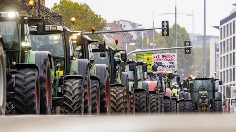 Landwirte fahren mit Traktoren bei einer Demonstration durch eine Innenstadt.