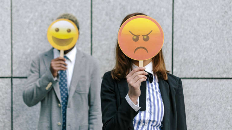 Zwei Menschen mit glücklichen und wütenden Emoji-Masken