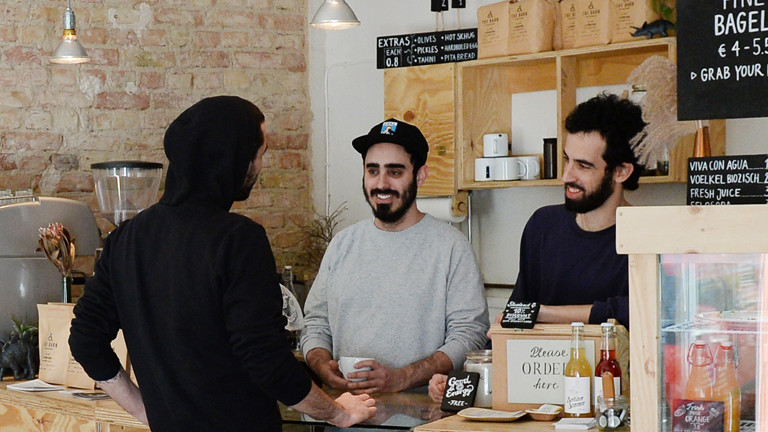 junge cafebetreiber mit einem kunden an der theke