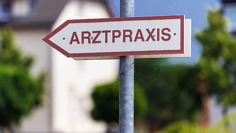 Ein Schild weist zu einer Arztpraxis