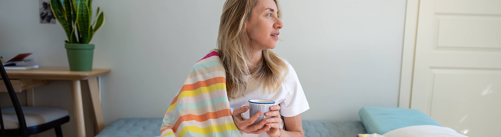Entspannte Frau im Bett, die Kaffee und Kontemplation genießt, sich an einem faulen Morgen ausruht.