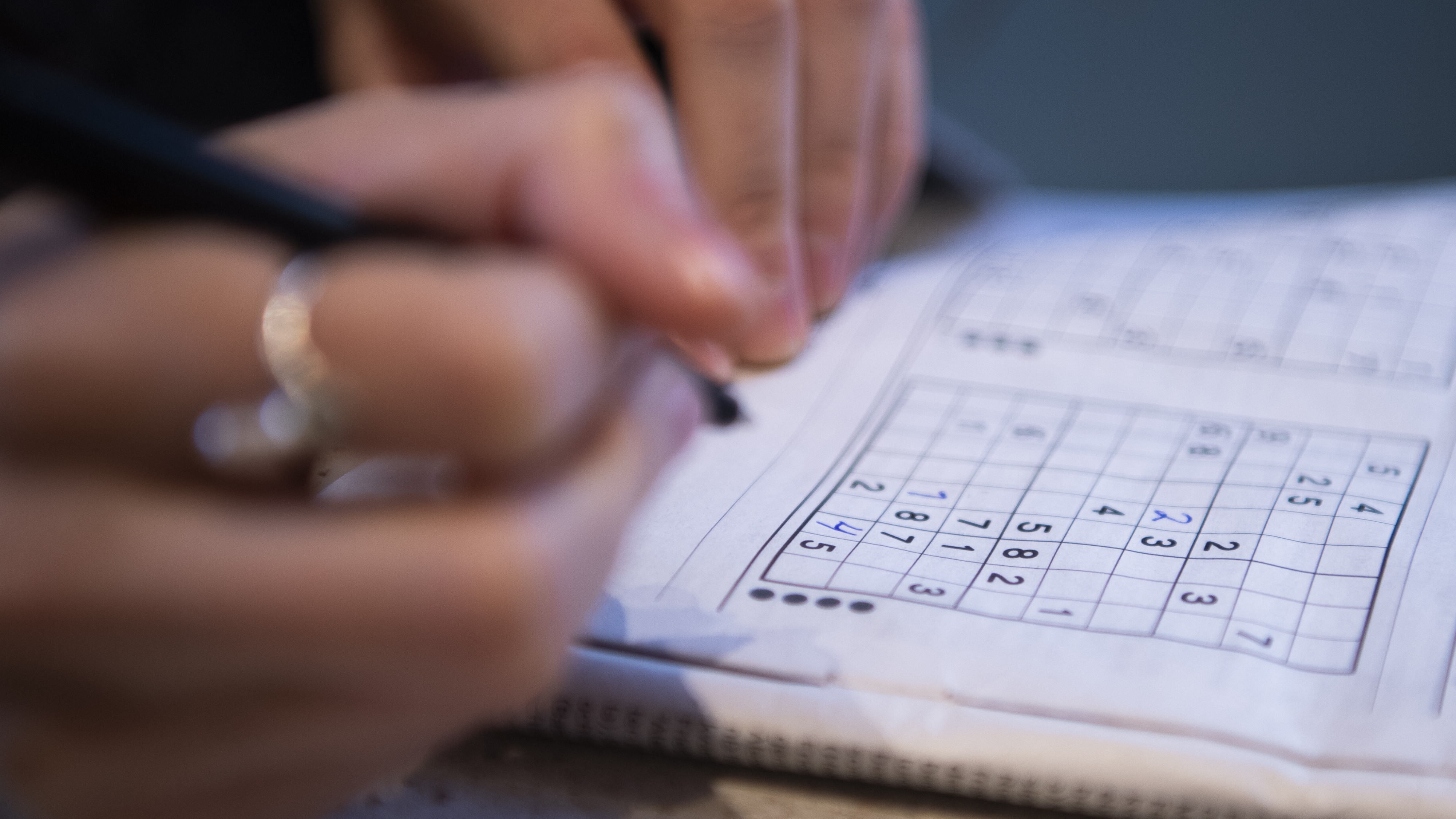 Nahaufnahme der Hände einer jungen Frau, die ein Sudoku-Rätsel löst