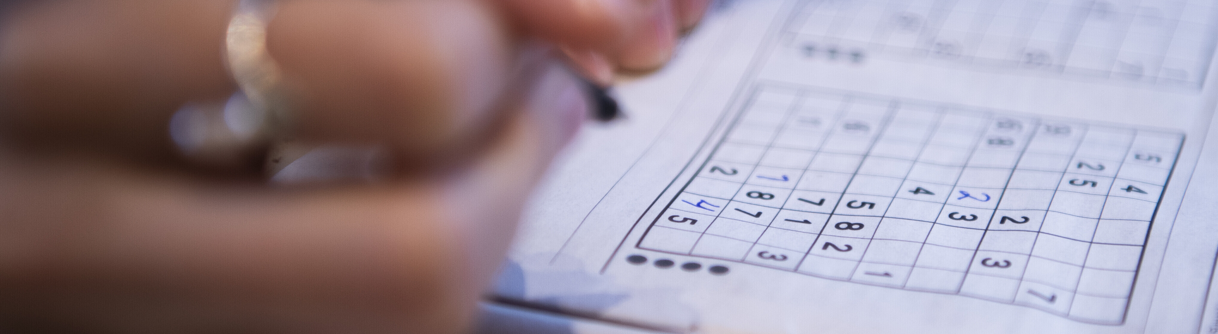 Nahaufnahme der Hände einer jungen Frau, die ein Sudoku-Rätsel löst