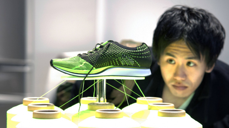 Ein Mann schaut sich einen ausgestellten Schuh der Marke Nike Flyknit Racer by Nike an.