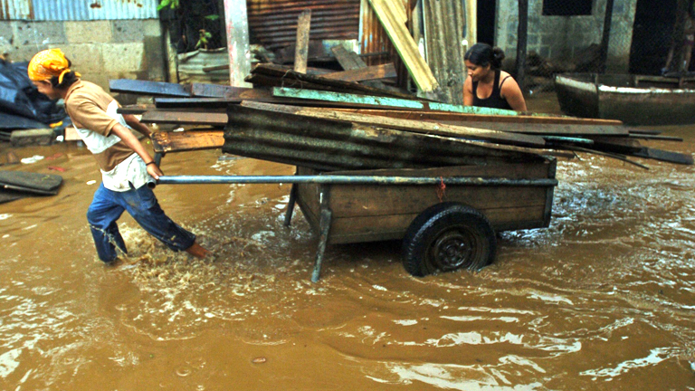 Zwei Frauen ziehen Karren durch überschwemmte Straße in Nicaragua