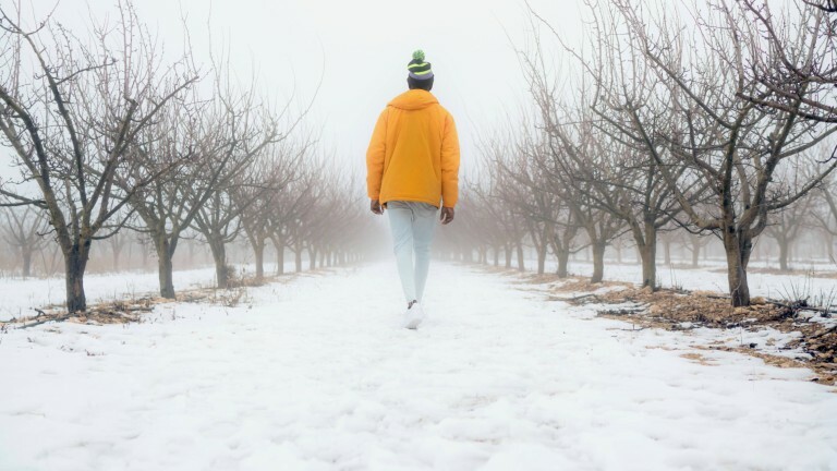 Ein Mann geht alleine in einer winterlichen Landschaft spazieren