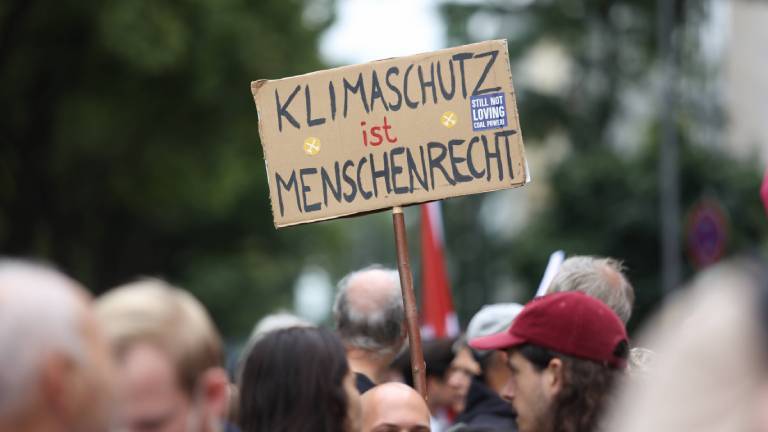 Ein Demonstrant in Köln hält ein Schild hoch, auf dem steht: Klimaschutz ist Menschenrecht