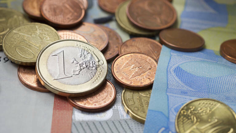 Münzen und Geldscheine liegen ausgebreitet